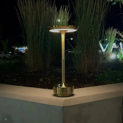Cordless table lamp with aluminum body on an outdoor dining table