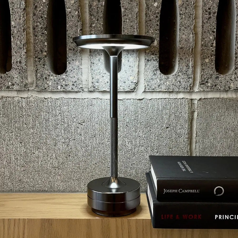 Cordless table lamp with aluminum body on an outdoor dining table