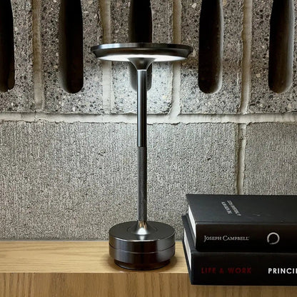 Cordless table lamp with aluminum body on an outdoor dining table
