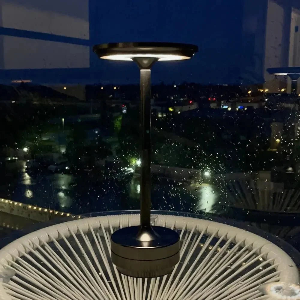 Cordless table lamp with aluminum body on an outdoor dining table