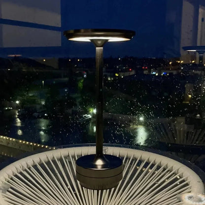 Cordless table lamp with aluminum body on an outdoor dining table