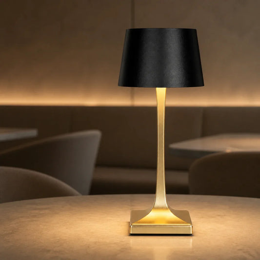 Gold and black IP54 cordless restaurant table lamp glowing on a dining table